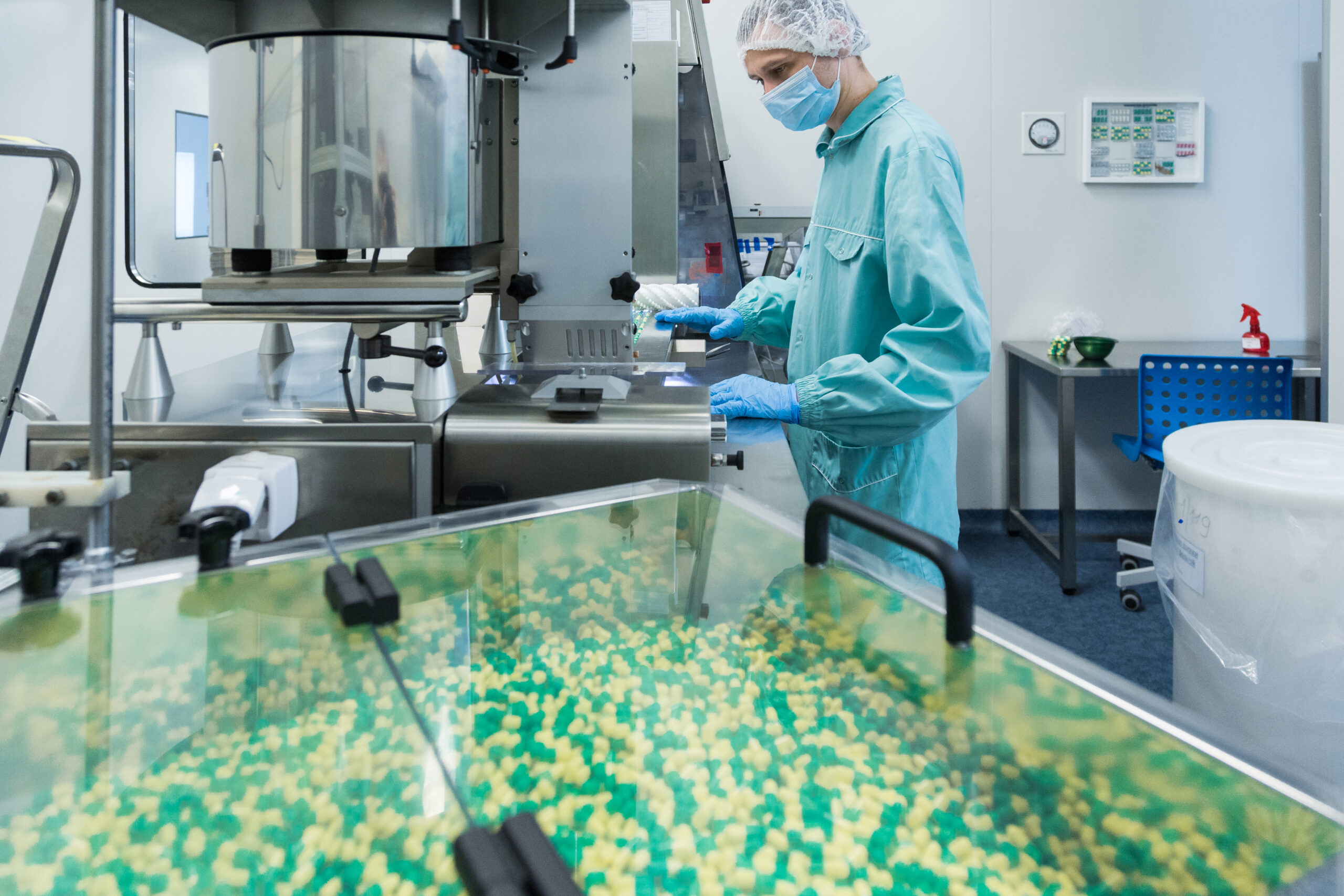 Pharmaceutical technician in sterile environment working on production of pills at pharmacy factory